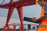 trabajadores de pie comprobando junto a la grúa pórtico